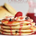 Enjoy this delicious and beautiful Banana and Dark Chocolate Chip Pancakes Recipe for a special occasion, or just because! Topped off with a Fresh Raspberry Syrup