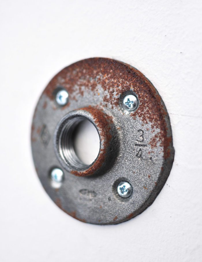 Metal Flange attached to the wall for hanging rods to create a shelf.