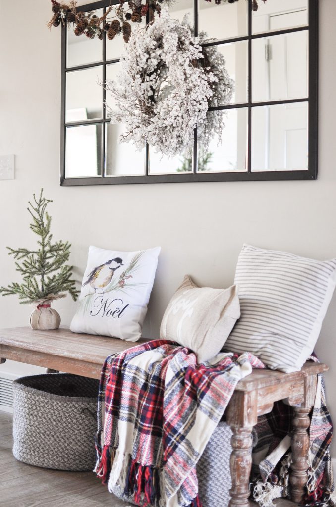 Take a tour through a simple farmhouse style Christmas Entryway. A basic bench, throw pillows, and a blanket create this cozy entrance! 