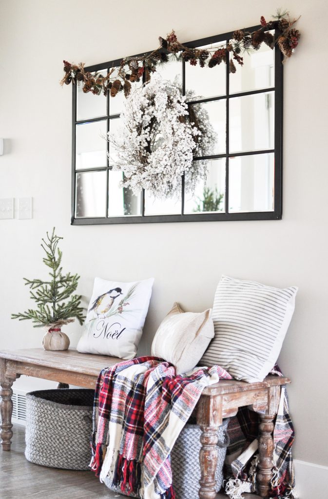 Take a tour through a simple farmhouse style Christmas Entryway. A basic bench, throw pillows, and a blanket create this cozy entrance! 