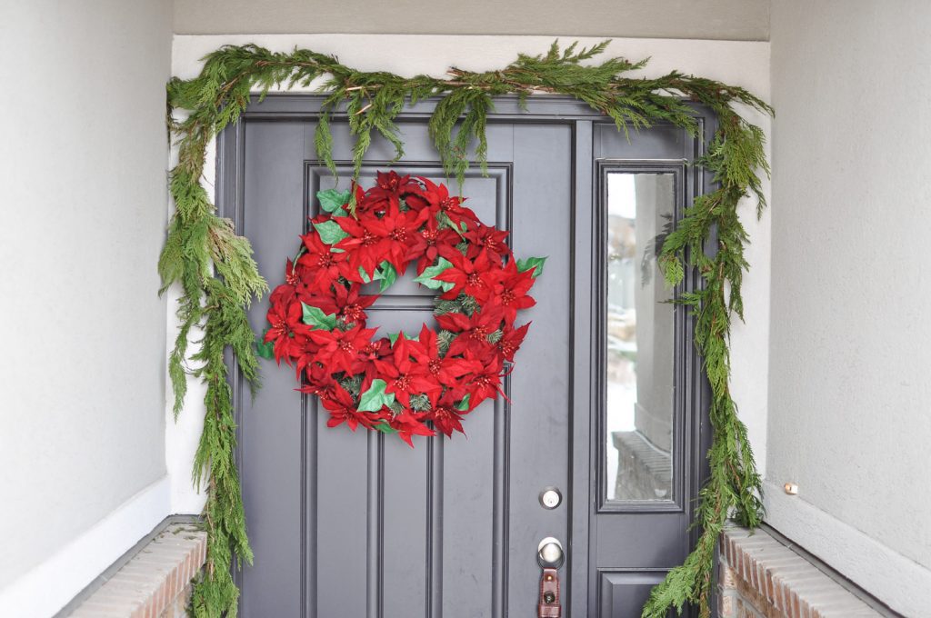 Looking for simple Porch Decorating Ideas? Create a classic appeal with these traditional poinsettias and cedar garland for a Classic Christmas Porch.