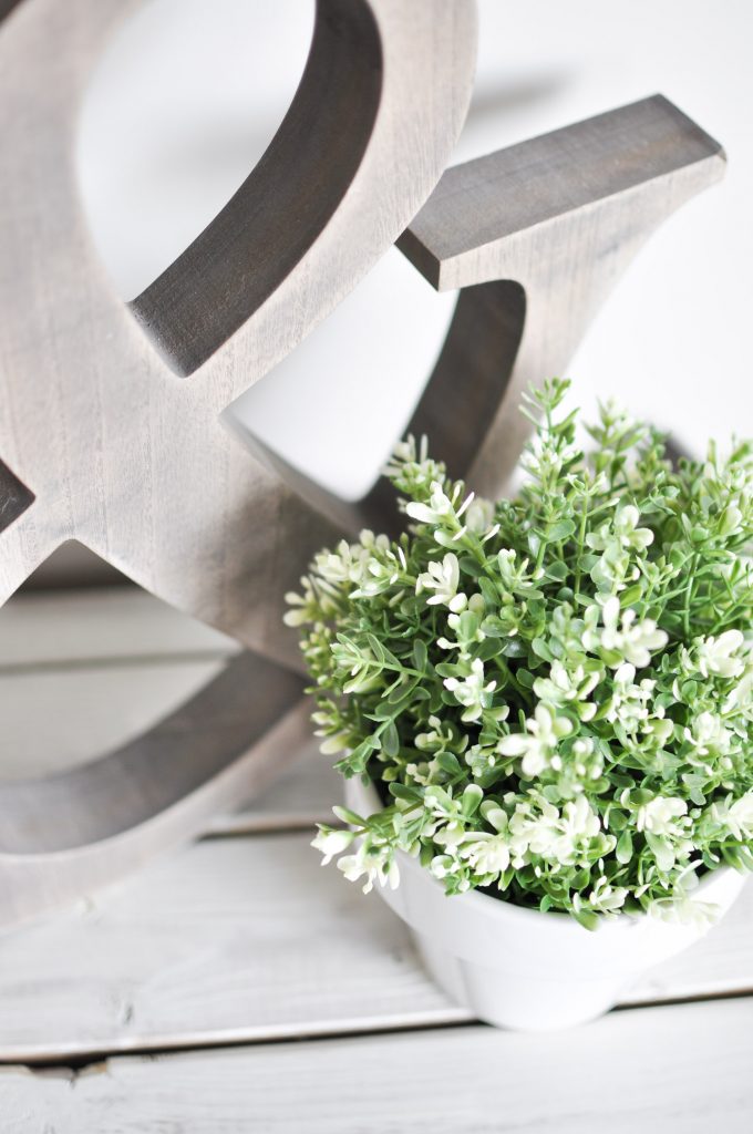 This Simple Summer Mantel is decorated using simple whites and greens to celebrate the growth of the season mixed with a few wood tones for coziness!