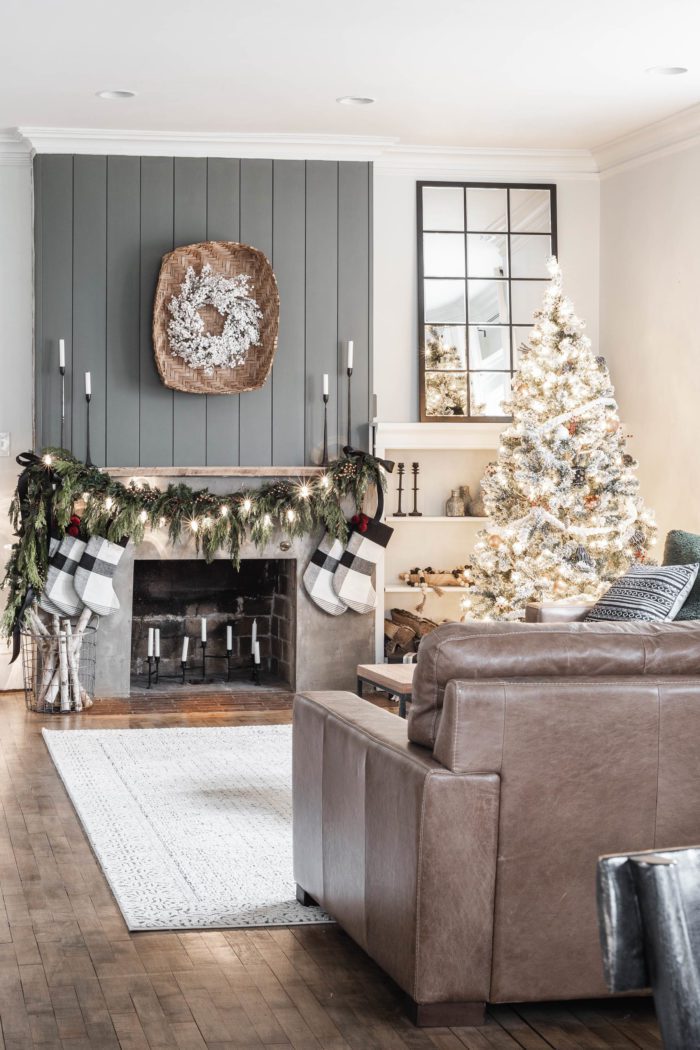 leather sofa, shiplap and concrete fireplace with fresh Christmas Garland. Modern Rustic Christmas Decor