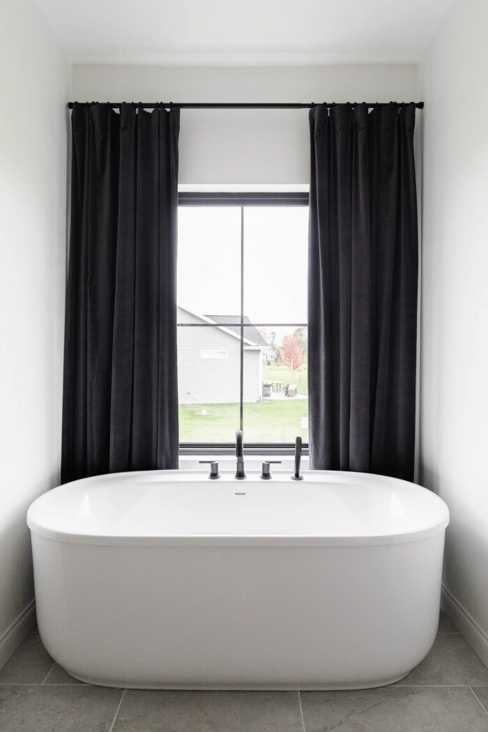 black velvet curtains in master bathroom behind freestanding tub.