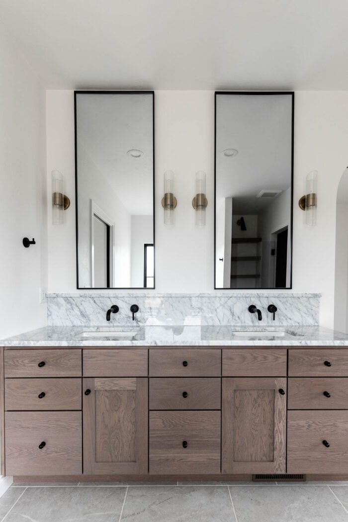 Extra Tall Vanity mirrors in bathroom with marble backsplash and ledge. 